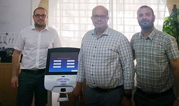 three people standing besides a intro self service kiosk