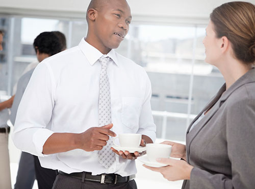 En man och en kvinna diskuterar affärer och håller i varsin kopp kaffe